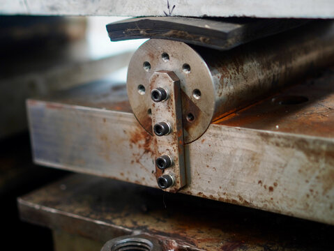 Close-up view of a heavy-duty steel roller support mechanism configured for structural flexural bending test in a materials testing laboratory