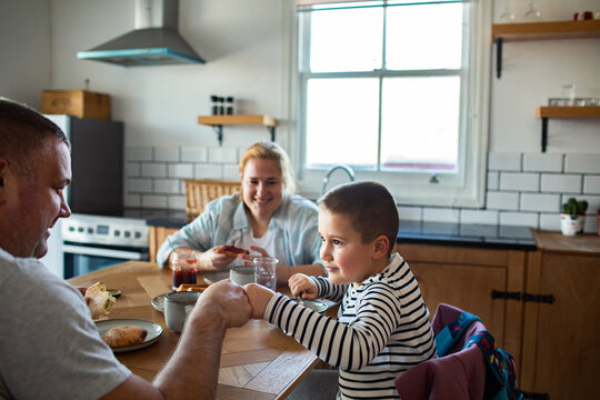 Parents and son sharing breakfast in home kitchen