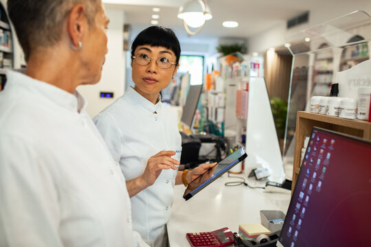 Pharmacists discussing inventory with tablet in modern pharmacy