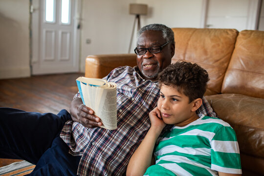 Grandfather reading a book with grandson at home