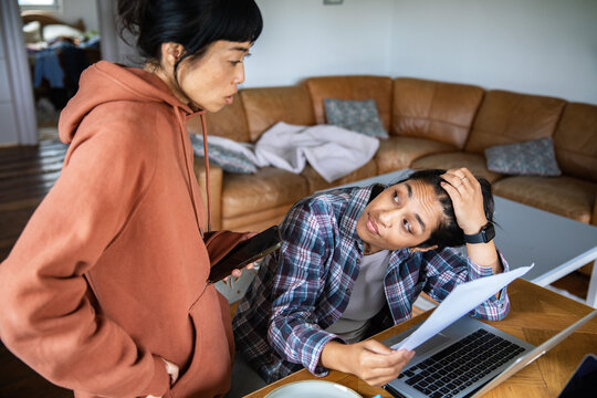 Stressed partners discussing finances in living room