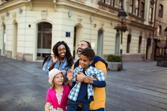 Smiling parents with son and daughter exploring city street