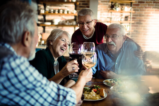 Senior friends toasting with wine at cozy restaurant dinner