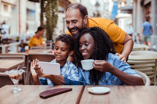 Parents and child video chatting at outdoor cafe