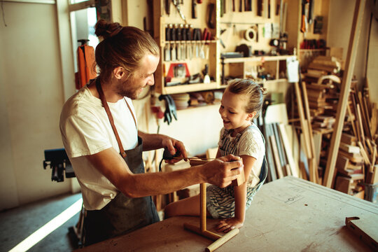 Father teaching daughter woodworking in home workshop