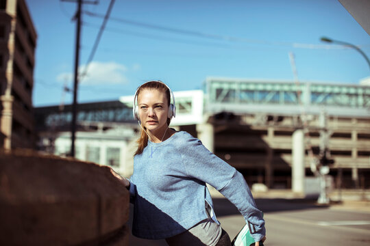 Young woman stretching before run on city street