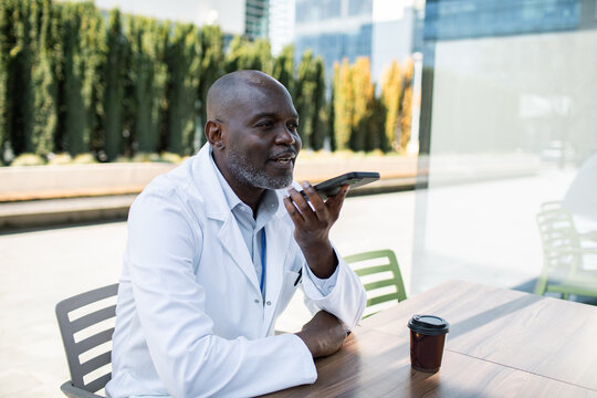 Doctor using smartphone voice assistant at outdoor table