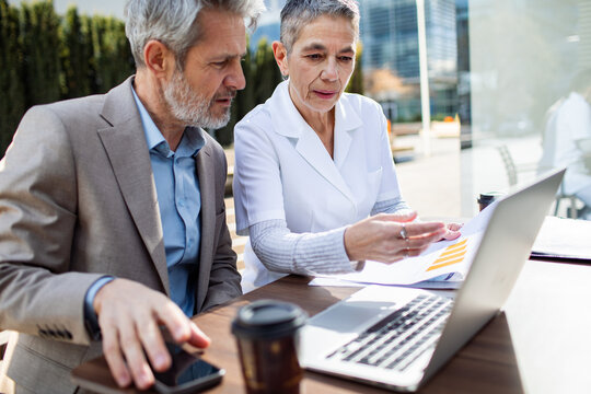 Two senior professionals reviewing financial report at outdoor cafe