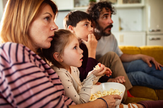 Family watching tv together at home with popcorn