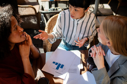 Three businesswomen discussing data at cafe table