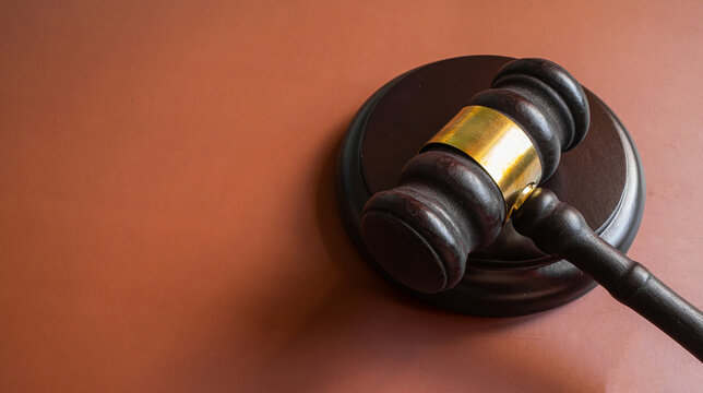 Wooden judge gavel with gold band on brown background with bokeh, court justice and legal system concept