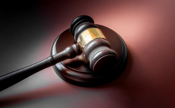 Wooden judge gavel with sound block on dark background with dramatic side lighting, court justice and law concept
