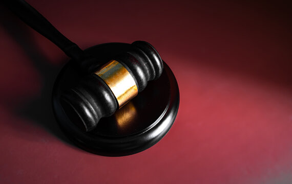Wooden judge gavel on dark red burgundy gradient background with dramatic lighting, court and legal justice concept
