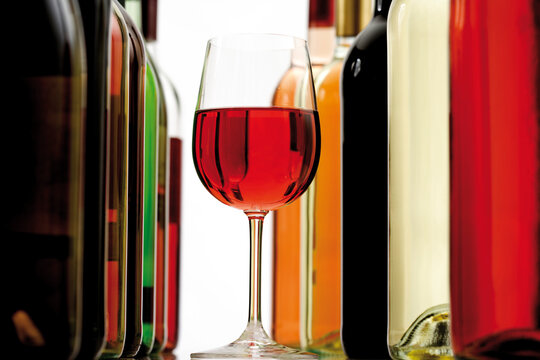 Glass of red wine between wine bottles, close-up
