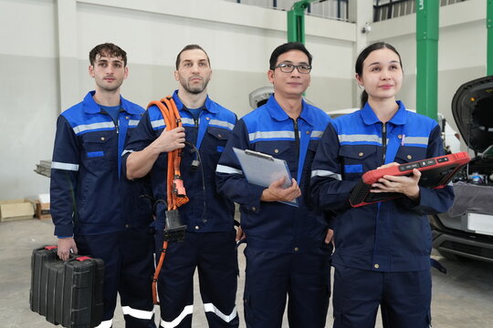 Team of EV Technicians with Diagnostic Equipment and High Voltage Cable in Electric Vehicle Workshop