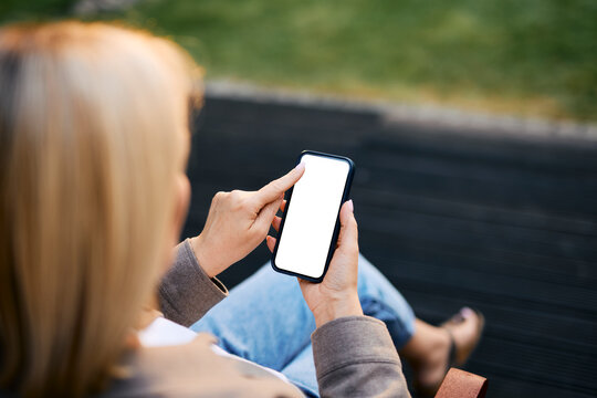 Person relaxing outdoors holding mobile phone with blank screen on terrace