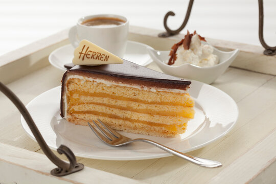 Slice of Herrentorte with whipped cream and cup of coffee in tray, close up