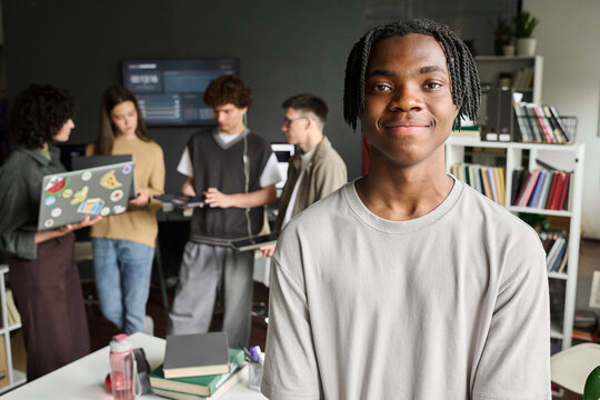 A male student smiles at the camera in the university classroom