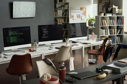 Empty modern office features computers displaying programming code