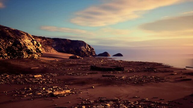 warm sunset sea stacks pebble beach with pastel sky and low light casting long shadows across gravelly shore, distant islets silhouette against colorful