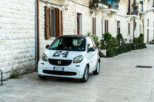 Bari, Italy - June 31, 2026: Smart Fortwo microcar with number 24 decal parked on cobblestone street in historic old town district during daytime