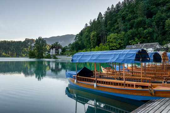 A wooden boat floats on Lake Bled near the distant castle