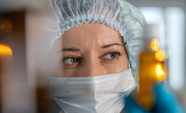 Doctor wearing mask and protective clothing examining vial in clinic