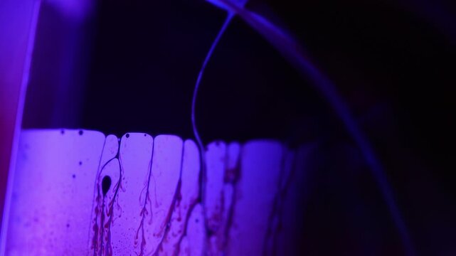 Glowing violet fluid boundary with intricate dark marble waveforms. Intense violet backlight illuminates a sharp diagonal liquid plane boundary.