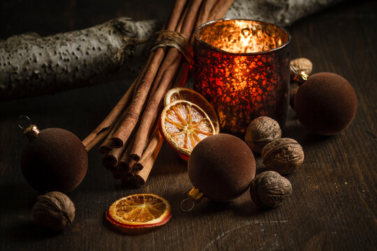 Christmas decoration with tea light candle, christmas tree balls, cinnamon sticks, slices of dried oranges and walnuts on wooden table, studio shot