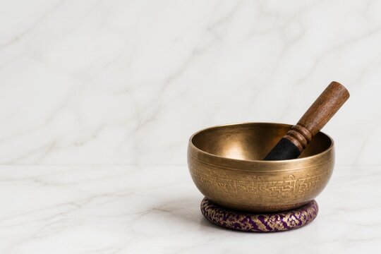 Tibetan singing bowl with wooden striker on a purple cushion. Traditional metal bowl for sound therapy and meditation practice. Holistic wellness and stress relief ritual concept.