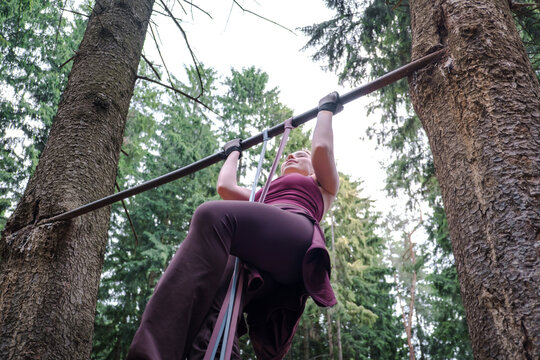 Woman does a pull up with a resistance band in the forest