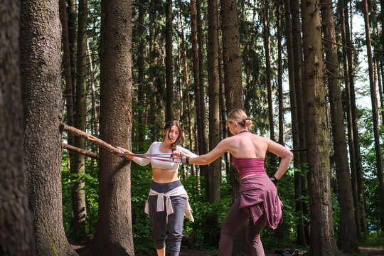 Women use a resistance band during a fitness break in the forest