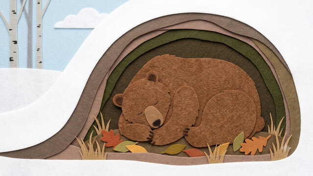 A sleeping brown bear rests in a layered, cut felt underground den with fallen autumn leaves, below a snowy winter landscape featuring birch trees.