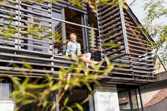Woman relaxing on balcony of her house