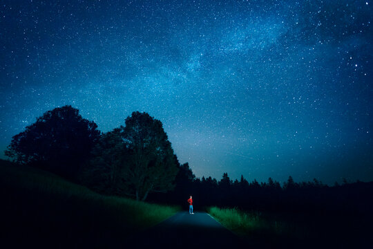 Austria, Mondsee, young man standing on empty street under starry sky