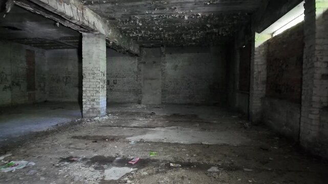 Interior of dark abandoned room with brick pillars and graffiti.