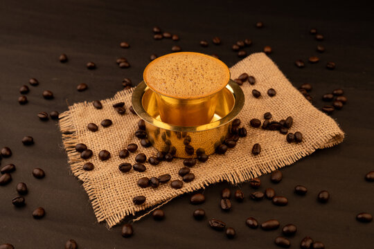 Traditional south indian Brass cup of coffee over beans background