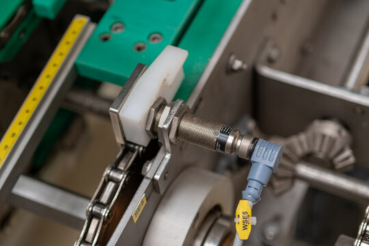 Detail of a sensor detecting a metal carrier on a link chain in a machine.