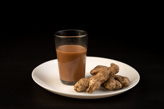 Traditional Indian ginger tea in a clear glass isolated on a black background