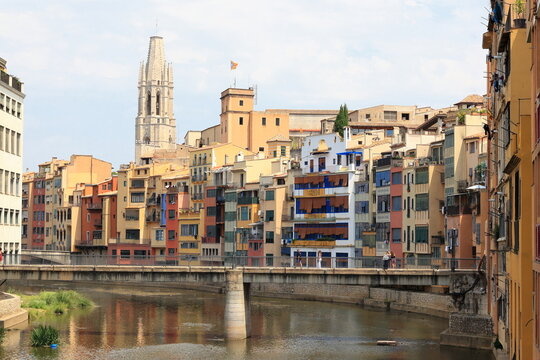 The Collegiate Church of Sant Feliu, as seen from the river Onyar, bridge and colorful buildings.