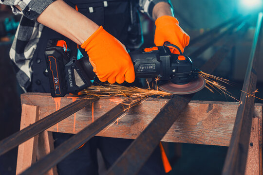 A man cuts metal using an angle grinder. Many sparks