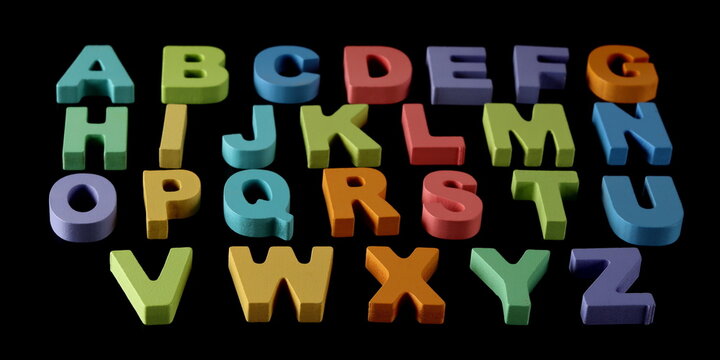 Colorful wooden alphabet letters isolated on black background and texture, side view, design element