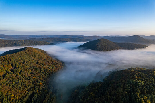Aerial view of the forested hills of the Palatinate Forest covered in morning fog near Wernersberg, Rhineland-Palatinate, Germany.
