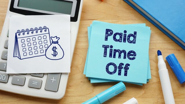 Paid time off note on desk with calculator, calendar and markers