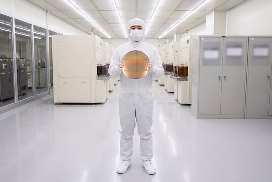 Cleanroom technician holding silicon wafer fab semiconductor bunny suit microchip fabrication chip manufacturing nanotechnology sterile tech