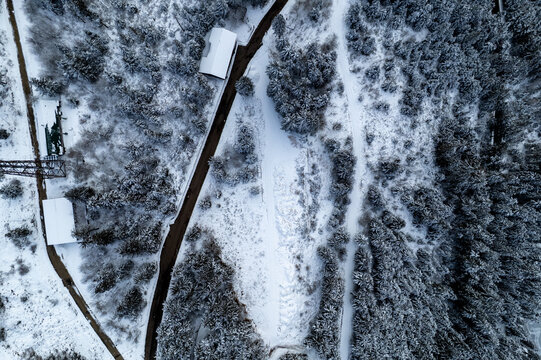 Aerial view of the snow-covered landscape near Seebach with dense evergreen forests, winding roads, and small buildings nestled in the winter scenery of Mummelsee, Baden-Wurttemberg, Germany.