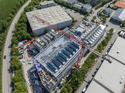 Aerial view of Portus Data Centers - Munich under construction with a large red crane, industrial rooftops, and surrounding roads in Kirchheim bei Muenchen, Bavaria, Germany.