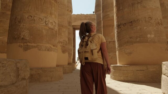 Woman tourist exploring Karnak Temple in Luxor walking between rows of ancient massive columns of Hypostyle Hall, Egypt tourism tour