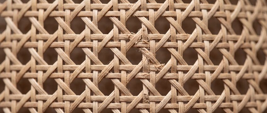 Woven rattan texture featuring intricate crisscross pattern of natural wicker fibers used for interior design and handmade basket craft