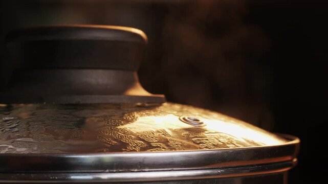 Stainless steel pot on a gas stove with boiling water and steam, cooking soup